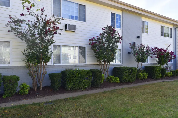 Beautiful apartment exterior featuring well-kept landscaping and flowering bushes.