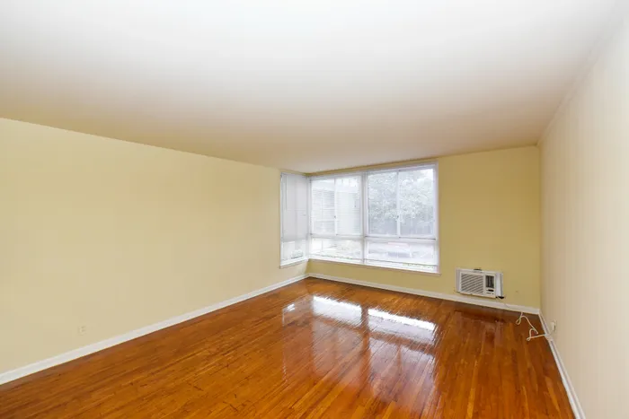 Spacious living room with hardwood floors, large windows, and abundant natural light.