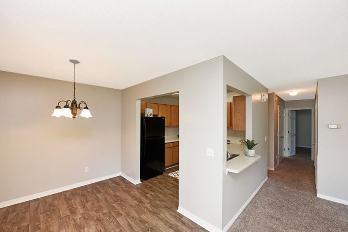 Bright apartment interior with modern kitchen and dining area, featuring elegant lighting and wood flooring.