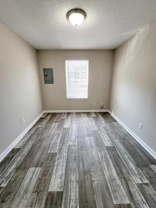 Bright room with stylish wood-patterned flooring and ample natural light from a square window.
