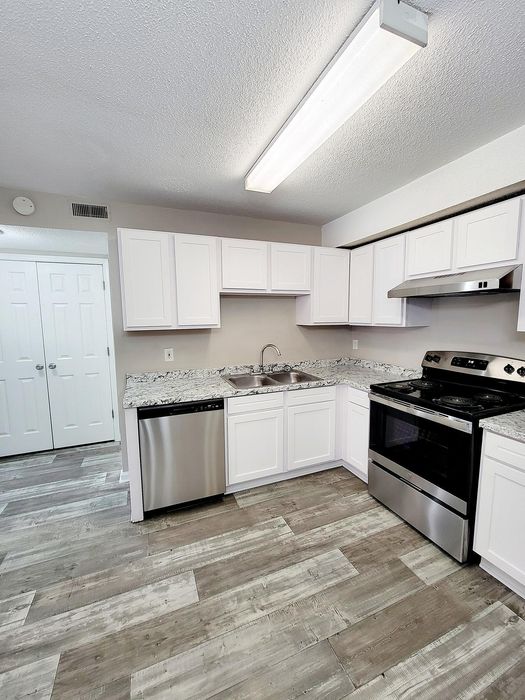 Sleek kitchen featuring stainless steel appliances, granite countertops, and modern cabinetry with hardwood flooring.