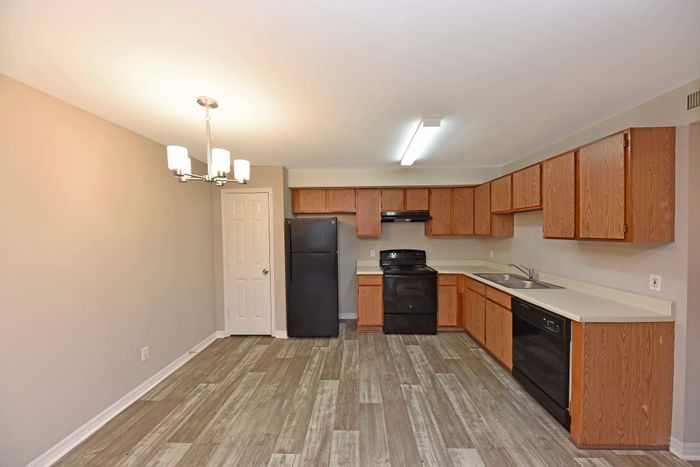 Modern kitchen with sleek wooden cabinets, black appliances, and contemporary lighting.