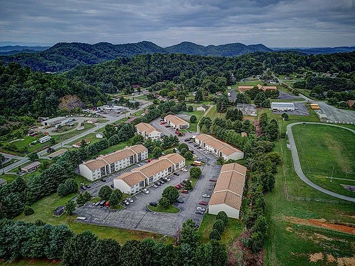 Aerial view of a charming residential community surrounded by lush greenery and rolling hills.
