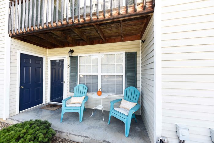 Cozy apartment patio with two blue chairs and a small table, complemented by a decorative orange pumpkin.