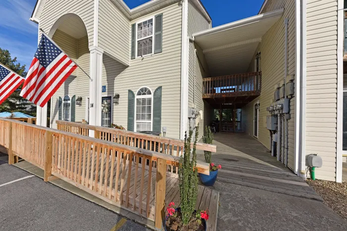 Inviting apartment entrance with a wooden ramp and American flags.