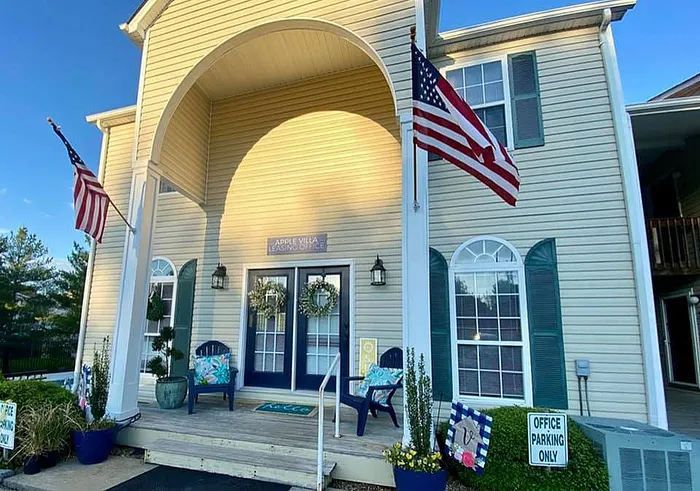 Elegant entrance of a leasing office with decorative wreaths, American flags, and potted plants.