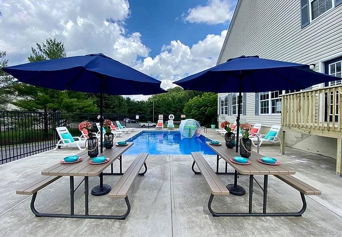 Inviting outdoor pool area with elegant seating, vibrant umbrellas, and lush greenery.