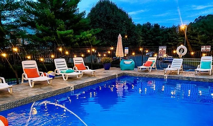 Inviting outdoor pool surrounded by lounge chairs and ambient string lights at dusk.