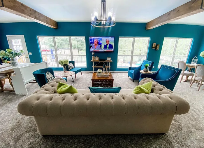 Inviting living room with plush seating, vibrant blue walls, and large windows offering natural light.