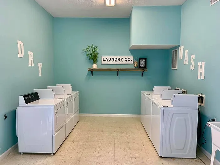 Bright and stylish laundry room with turquoise walls, featuring multiple washing and drying machines.