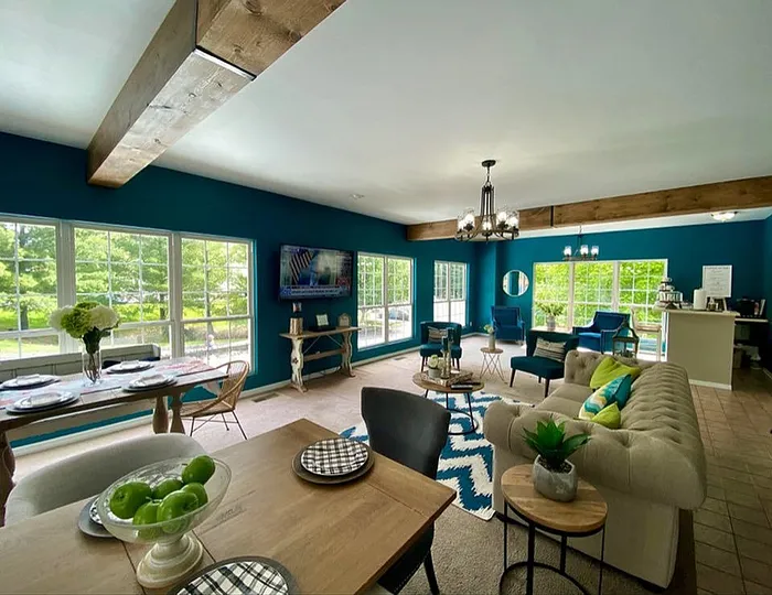 Bright and spacious living area with elegant furniture, modern decor, and large windows overlooking lush greenery.