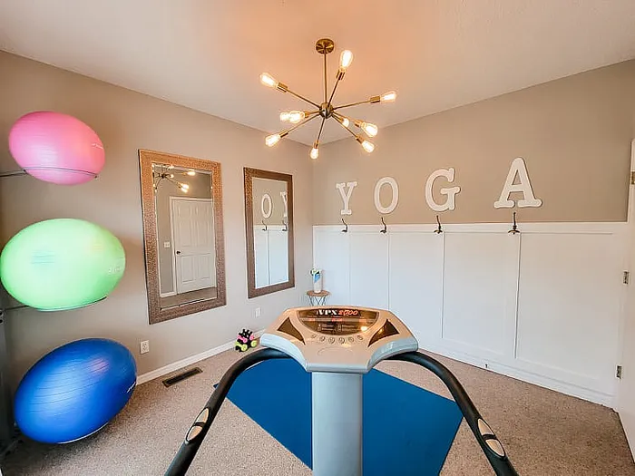 Bright yoga room with exercise balls, mirrors, and a modern lighting fixture.