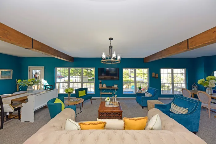 Spacious and elegantly decorated living room with plush seating, large windows, and a contemporary chandelier.
