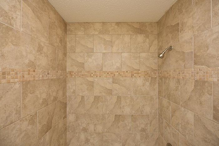 Stylish shower enclosure featuring refined beige tilework and a decorative trim.