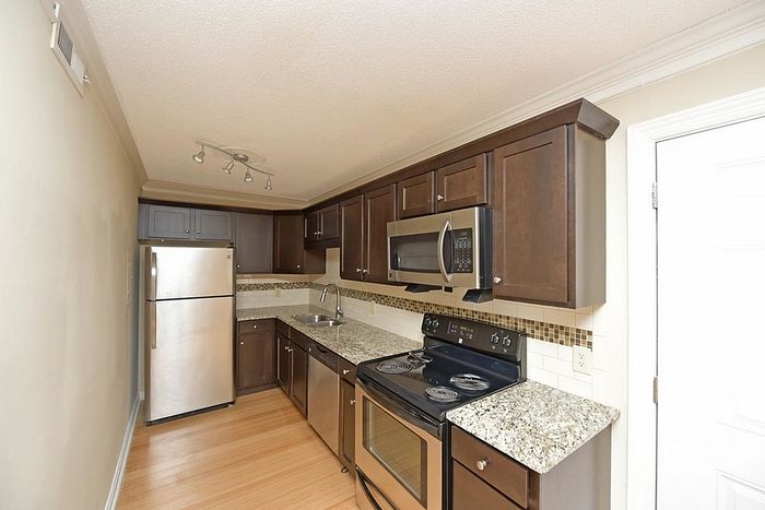 Contemporary kitchen with stainless steel appliances, granite countertops, and elegant dark wood cabinetry.