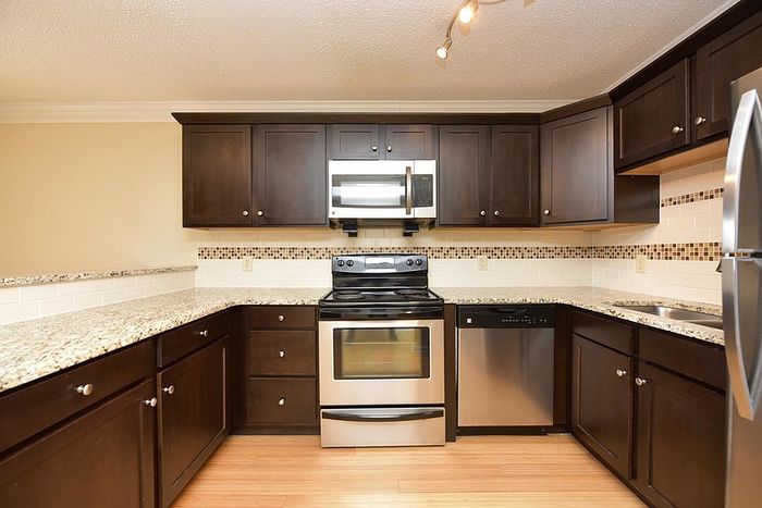 Contemporary kitchen with dark wood cabinets, granite countertops, and stainless steel appliances.