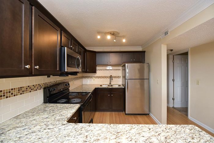 Modern kitchen with dark wood cabinets, granite countertops, and stainless steel appliances.
