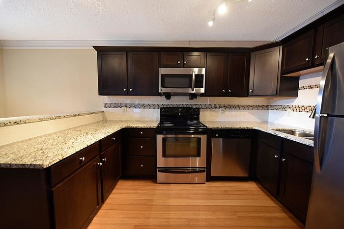 Modern kitchen with dark wood cabinets, stainless steel appliances, and granite countertops.