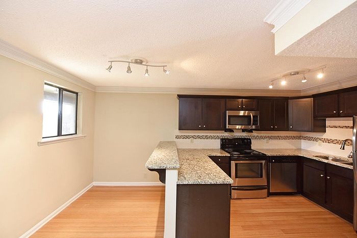Contemporary kitchen with dark wood cabinets, stainless steel appliances, and elegant granite countertops.
