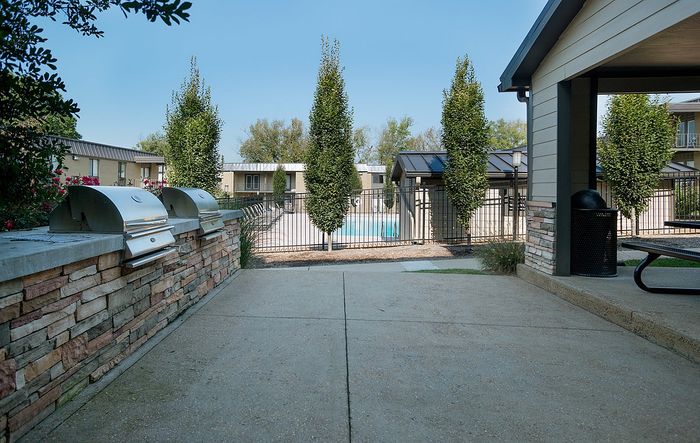 Inviting outdoor patio area featuring modern grills and a view of the glistening pool beyond.