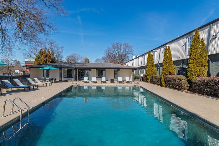 Inviting outdoor pool area with lounge chairs and clear blue water against a bright, sunny sky.