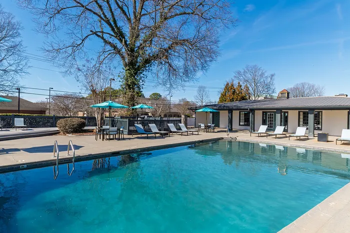 Inviting outdoor pool with sun loungers, umbrellas, and clear blue skies, ideal for relaxation.