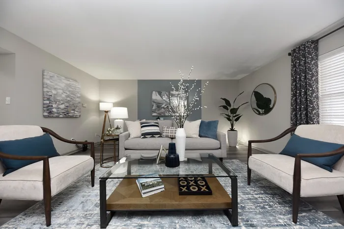 Chic living room with gray couches, stylish decor, and a glass coffee table.