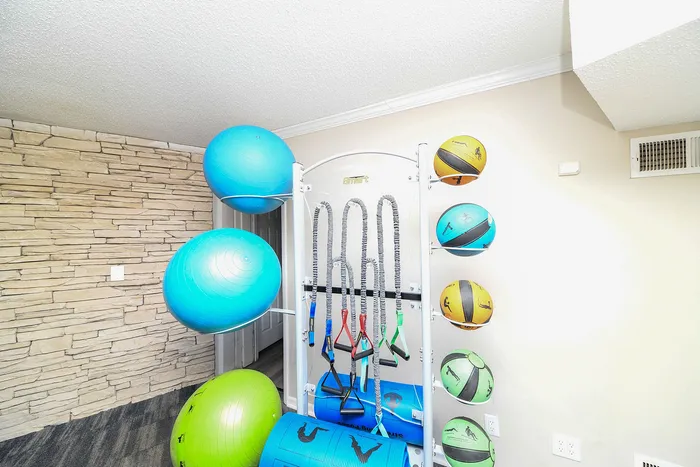 Bright home gym area featuring exercise balls and resistance bands against a stylish brick wall.