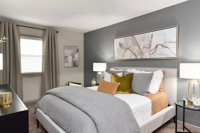 Luxurious bedroom featuring a plush bed with stylish pillows, ambient lighting, and modern artwork.
