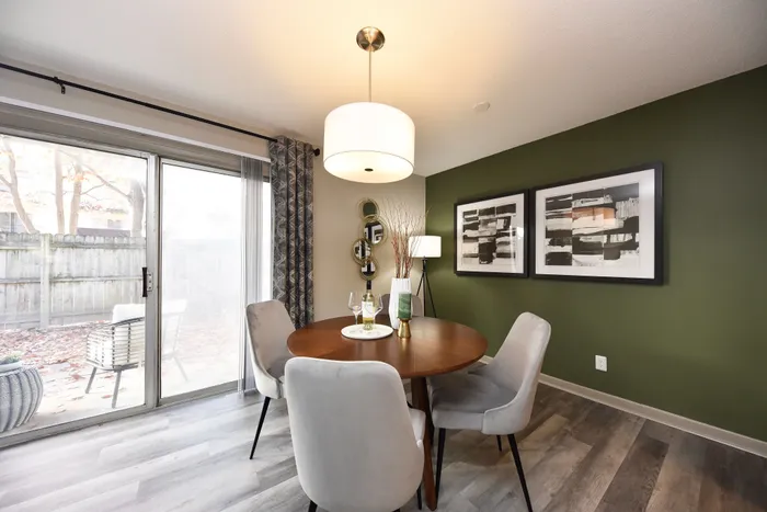 Elegant dining area with round table and stylish chairs, accented by modern decor and natural light from large sliding doors.