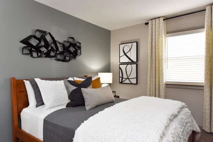Inviting bedroom with stylish decor, featuring a plush bed, contemporary art, and abundant natural light.