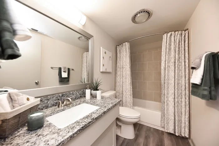 Stylish bathroom featuring a granite countertop, modern fixtures, and a tiled shower.