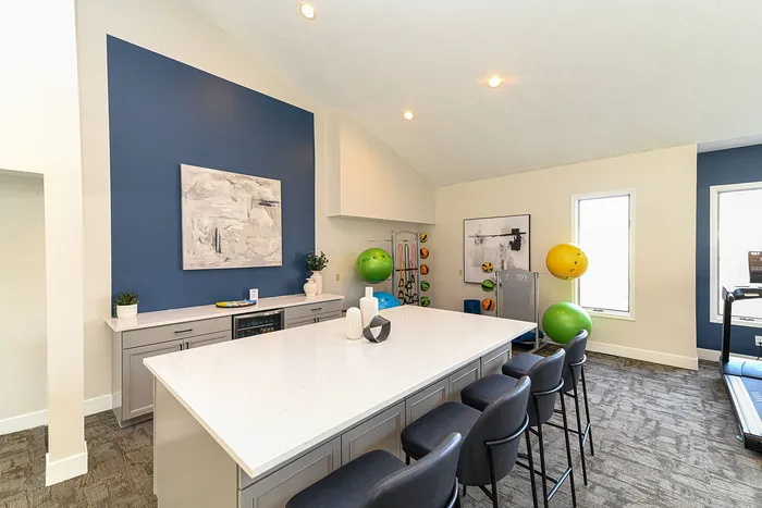 Modern fitness lounge with exercise equipment and sleek bar seating.
