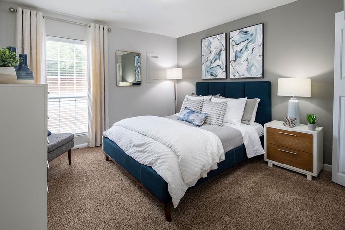 Elegant bedroom with plush bedding, modern art, and warm lighting.