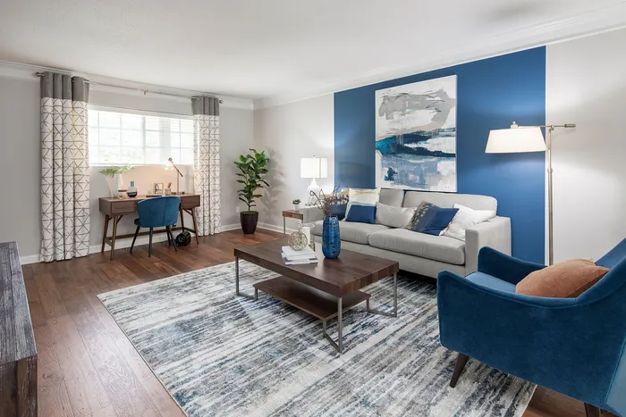 Stylish living room with a blue accent wall, contemporary furniture, and a cozy office nook.
