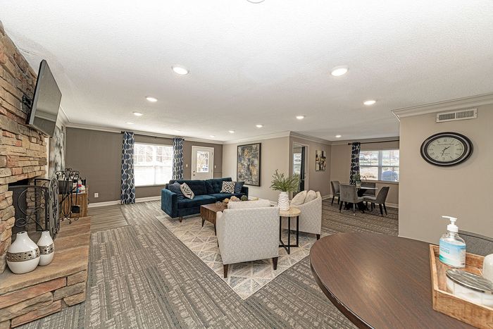 Spacious living room with contemporary design, featuring a cozy stone fireplace, elegant dining area, and stylish blue and gray decor.