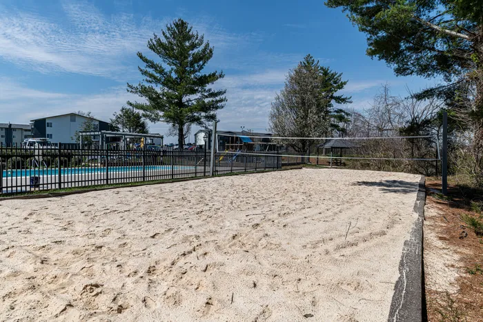 Inviting outdoor sand volleyball court with lush greenery and modern apartments in the background, perfect for leisure and fitness.