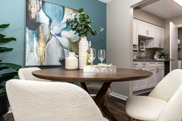 Chic dining area with modern art, cozy seating, and a stylish kitchen in the background, perfect for entertaining.