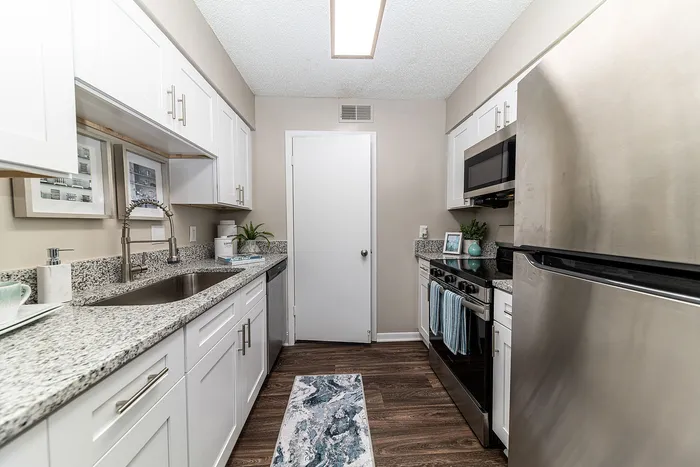 Contemporary kitchen with sleek stainless steel appliances, elegant granite countertops, and modern white cabinetry.