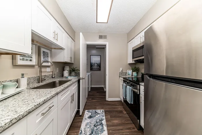 Sleek modern kitchen showcasing granite countertops, stainless steel appliances, and elegant cabinetry in a contemporary apartment.