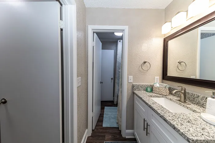 Elegant bathroom with a modern granite countertop, large mirror, and stylish lighting.
