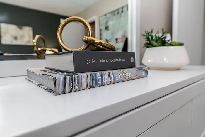 Elegant home decor with interior design books and stylish gold accents on a modern white table, complemented by a fresh green succulent.
