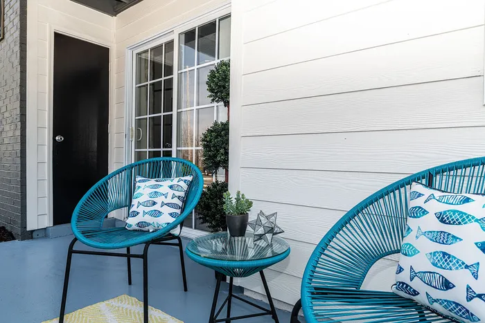 Charming patio with modern turquoise chairs, a glass-top table, and stylish fish-patterned cushions.