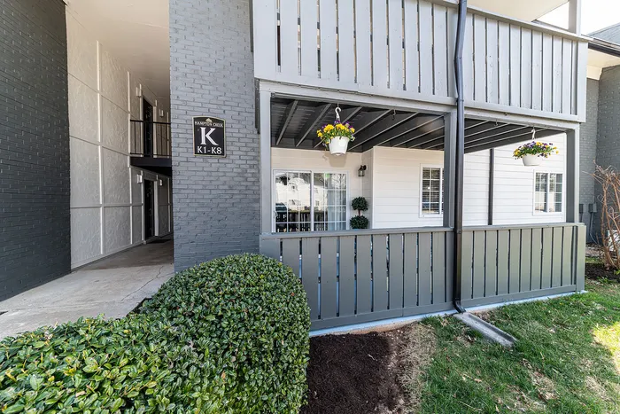 Charming apartment exterior with private balcony, lush greenery, and inviting hanging flower baskets.