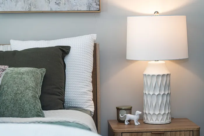 Cozy bedroom corner with designer lamp, plush pillows, and stylish decor.