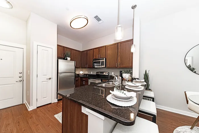 Contemporary kitchen with dark granite countertops, elegant pendant lighting, and stainless steel appliances.