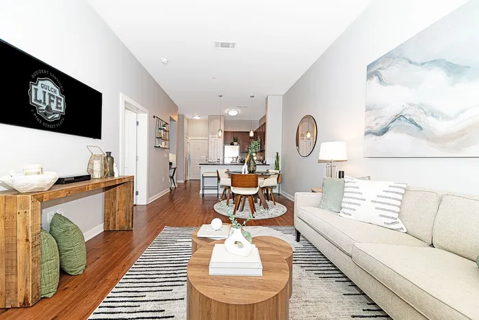 Bright and modern open-concept living space featuring elegant decor, a cozy seating area, and a stylish dining setup leading to a sleek kitchen.