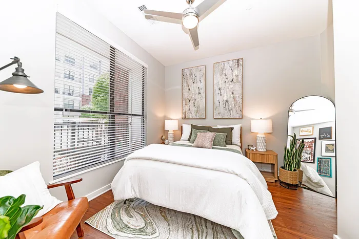 Bright and stylish bedroom with modern decor, featuring a cozy bed, large window, and elegant artwork.