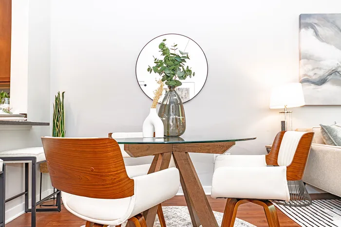 Elegant dining area with a glass-top table, modern wood chairs, and stylish decor, creating a cozy and inviting ambiance.