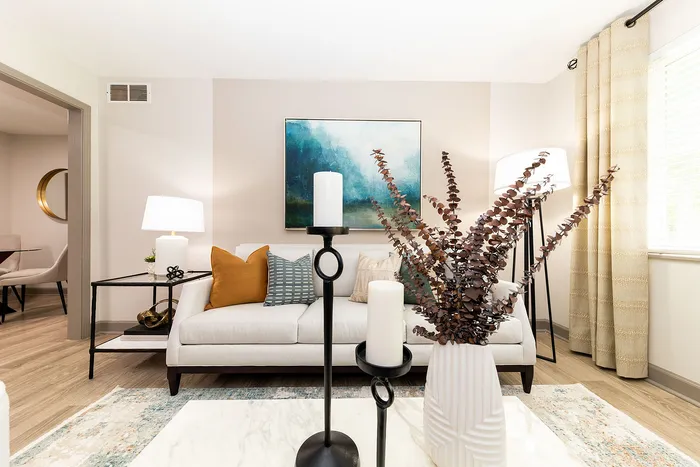 Bright, modern living room with elegant decor, featuring a cozy white sofa, chic floor lamp, and artistic wall painting.
